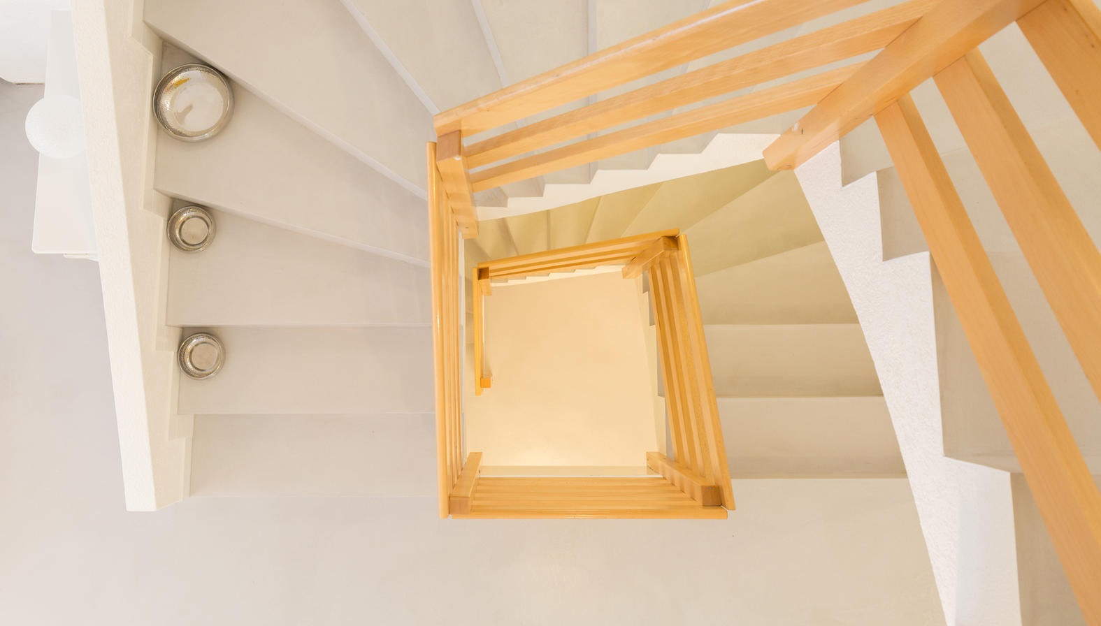 Blick von oben in ein Treppenhaus mit hell gespachtelten Stufen und Holzgeländer