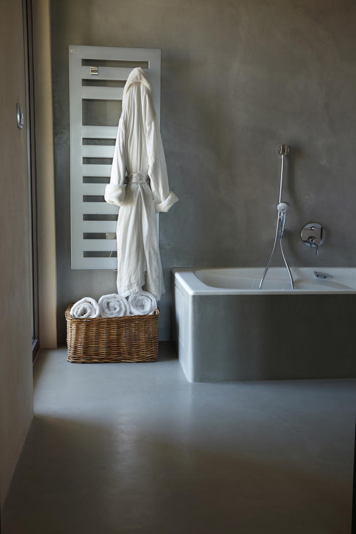 Badewanne und Wand in einheitlich grau gespachtelter Oberfläche