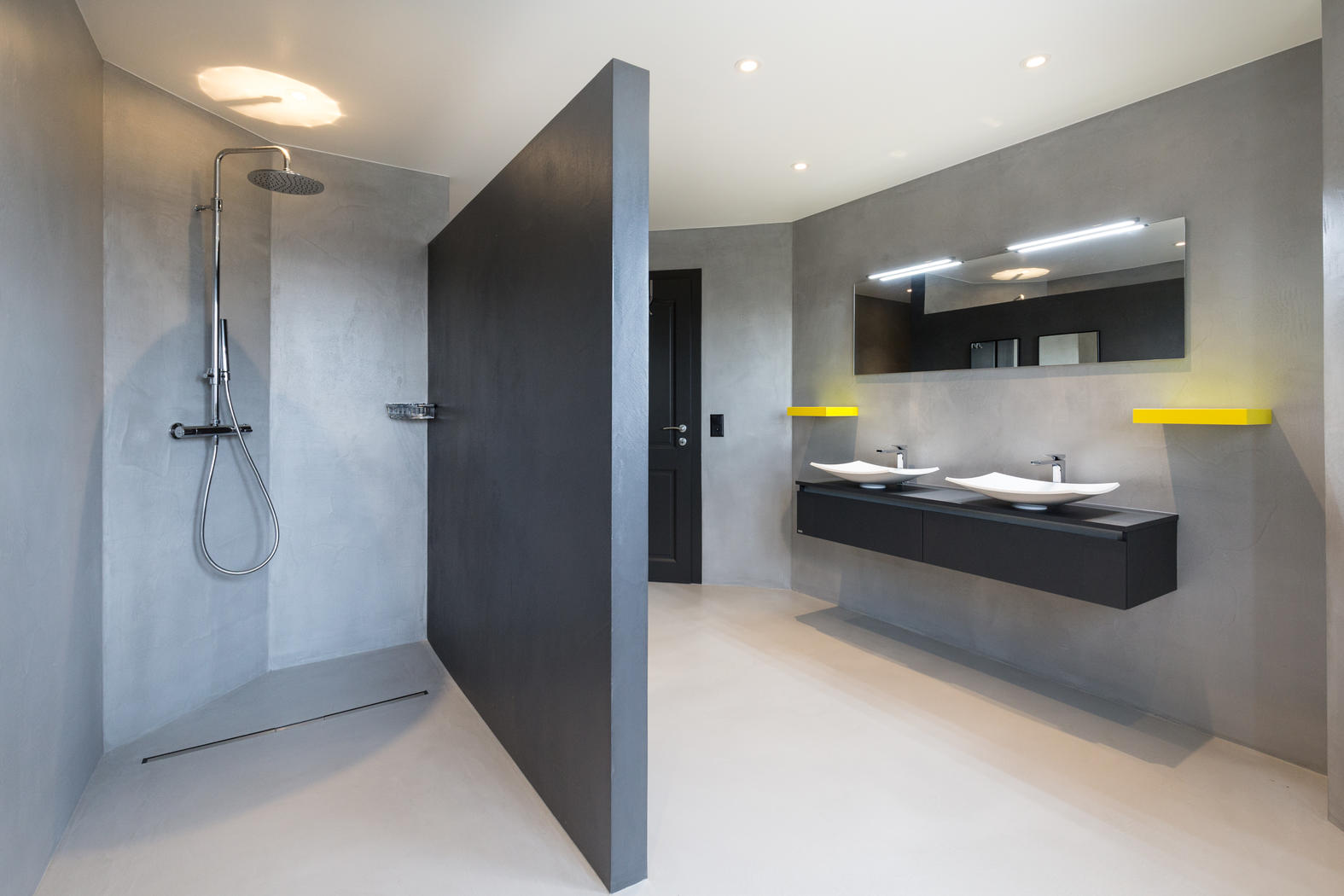 Graues Badezimmer, in dem Wände, Boden und die bodengleiche Dusche gespachtelt sind