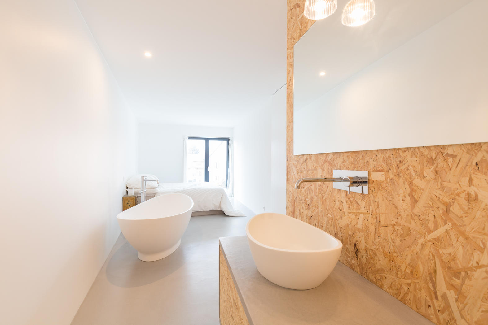 Heller Raum mit gespachteltem Boden, zwei freistehenden Waschbecken und einer Wand aus OSB