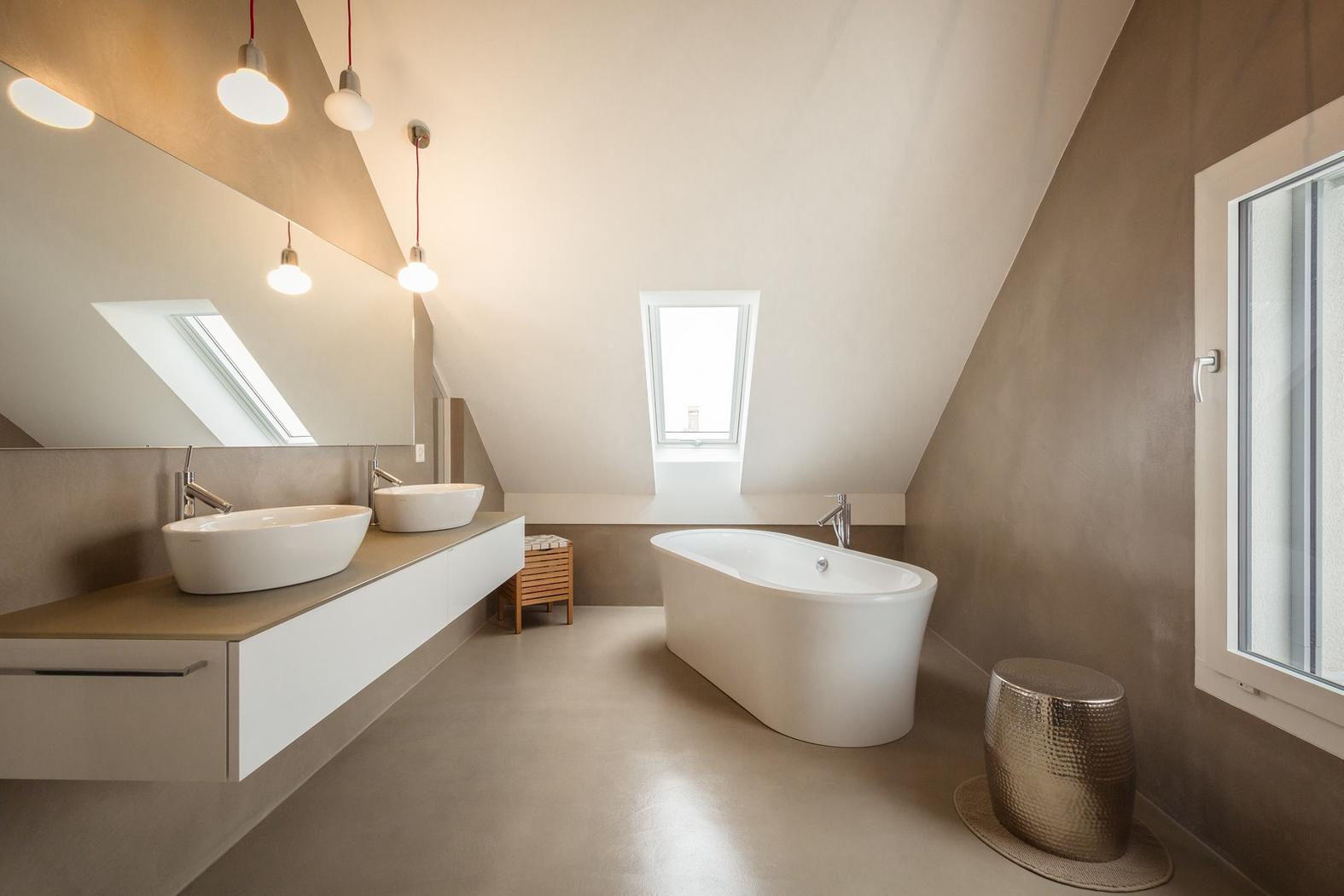 Badezimmer unter der Dachschräge mit freistehender Wanne und sandfarbenen Wänden